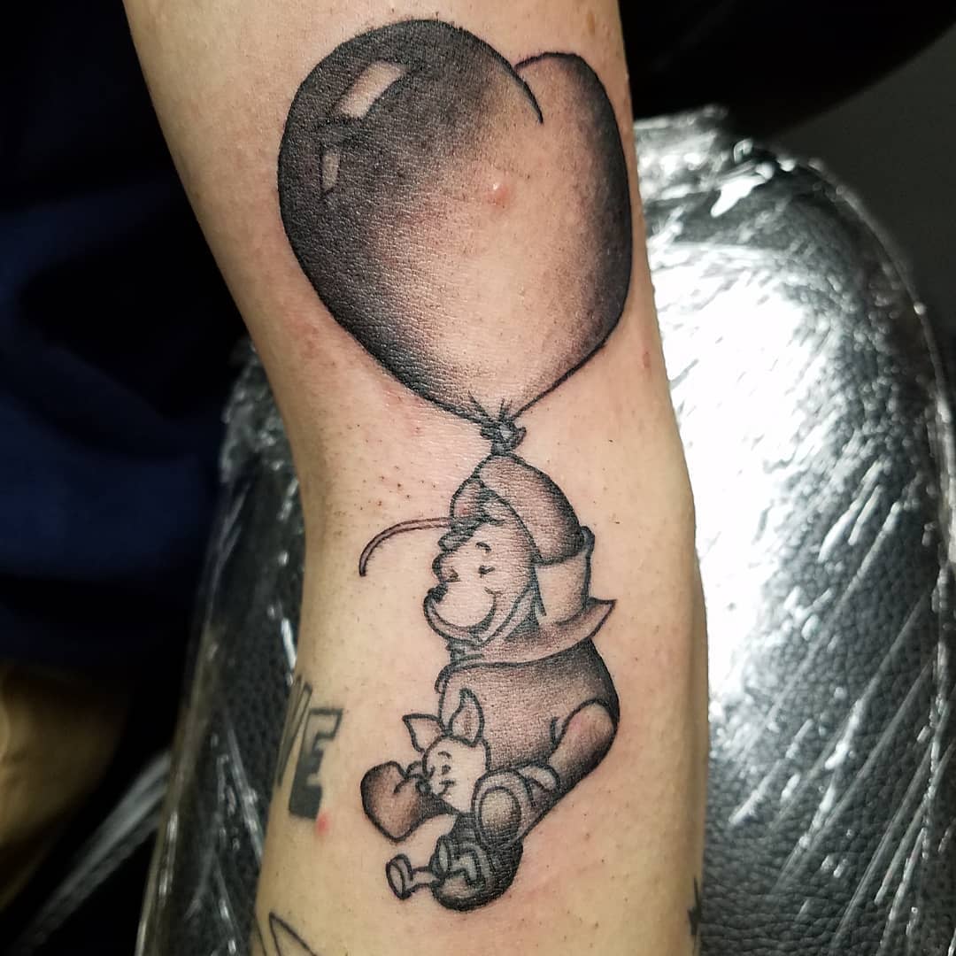 Tattoo of Winnie the Pooh holding Piglet, floating with a heart-shaped balloon